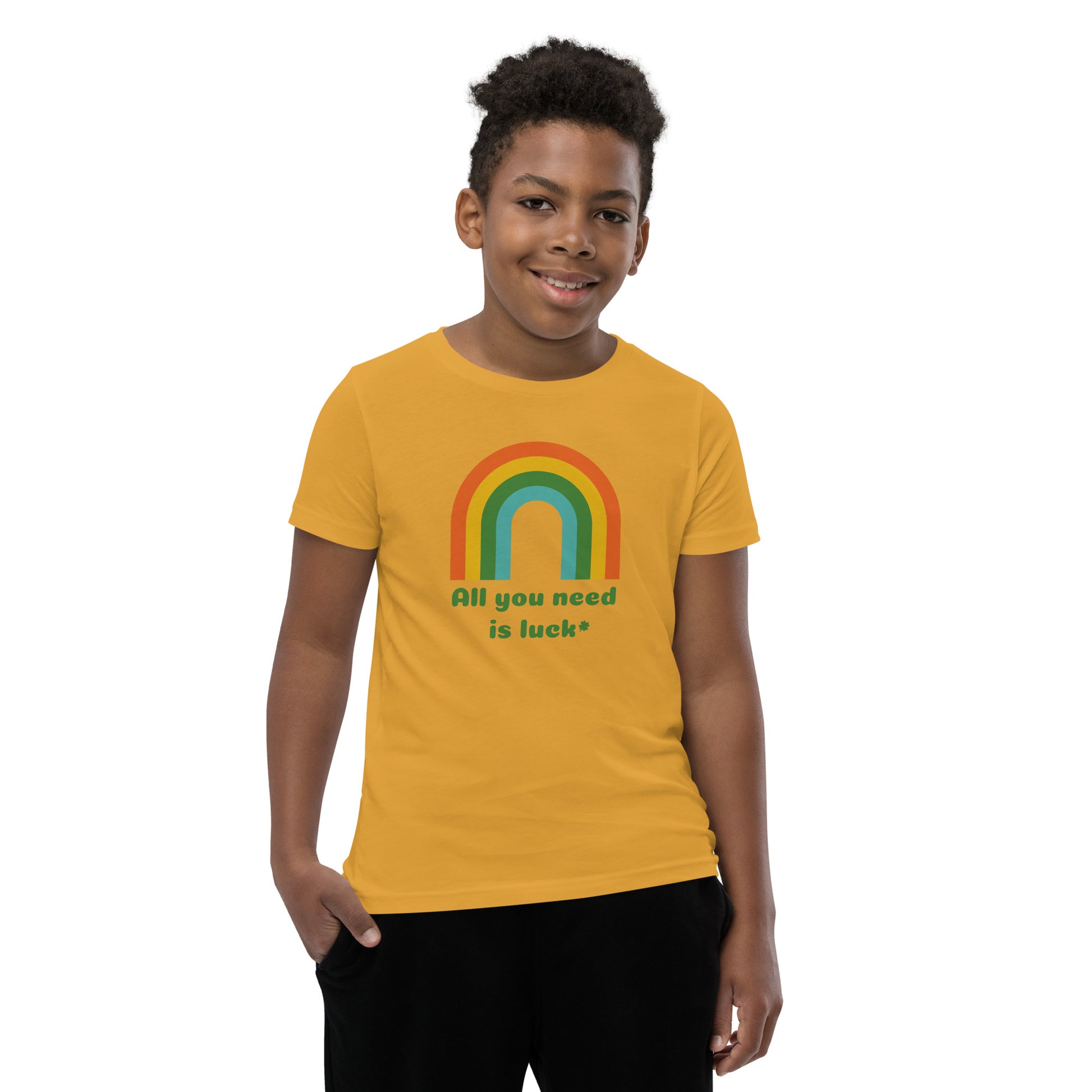 Kids St Patricks Day shirt featuring All You Need Is Luck phrase with lucky shamrock clover and rainbow design. Printed on Bella Canvas youth short sleeve tee available in black, athletic heather, white, and mustard colors for festive holiday outfits.