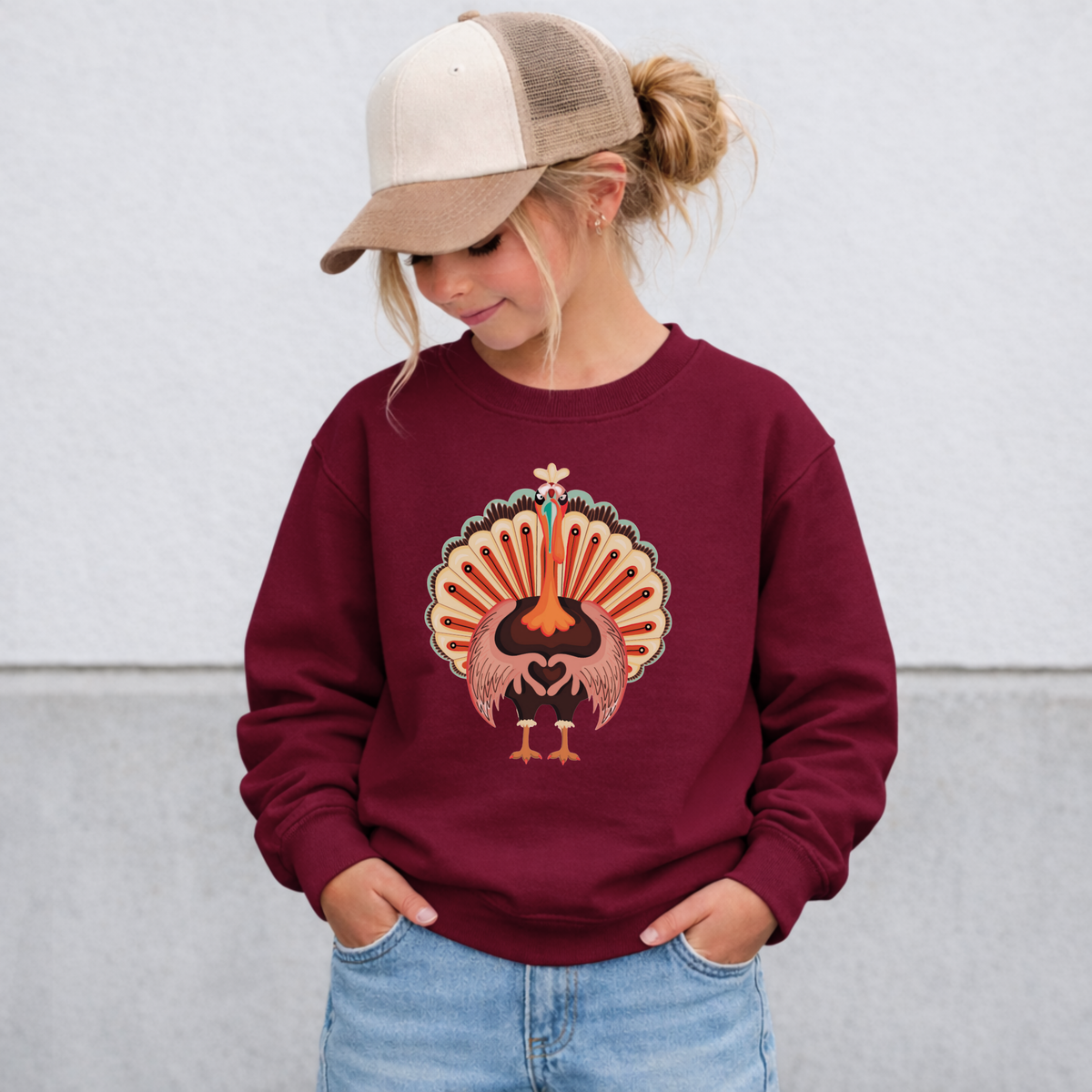 Cute youth turkey sweatshirt with colorful red, orange, brown and cream feathers and a heart shaped wing design, a fun Thanksgiving outfit for kids and tweens