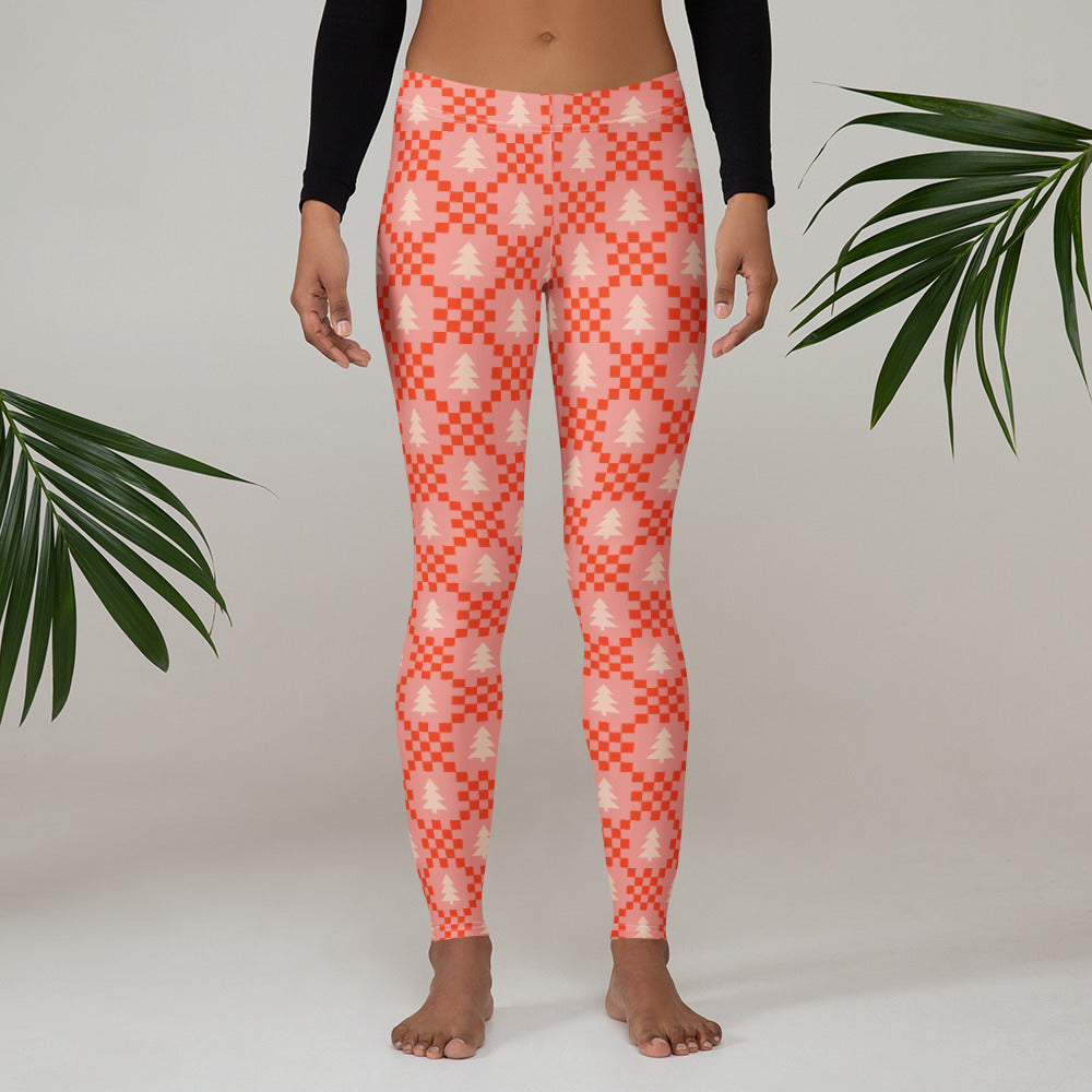 Women’s pink Christmas tree leggings featuring a playful holiday pattern with cream evergreen trees and red geometric details on a soft pink background. The festive design has a nostalgic Nordic Christmas sweater feel with a cheerful retro aesthetic. These full length leggings have a mid rise fit and stretchy fabric, making them perfect for Christmas morning, holiday parties, decorating the tree, family photos, Christmas shopping and cozy winter days.