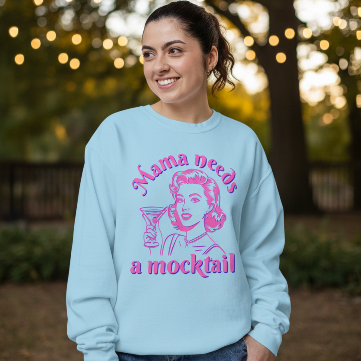 Light blue Comfort Colors crewneck sweatshirt featuring the “Mama Needs a Mocktail” graphic in vibrant pink and blue. The retro pop art illustration shows a stylish vintage inspired woman holding a cocktail glass, giving the sweatshirt a playful nostalgic personality. The relaxed everyday style works well with jeans, shorts, or leggings and makes a fun choice for expecting moms, mocktail lovers, sober curious women, or anyone who enjoys a colorful statement sweatshirt.