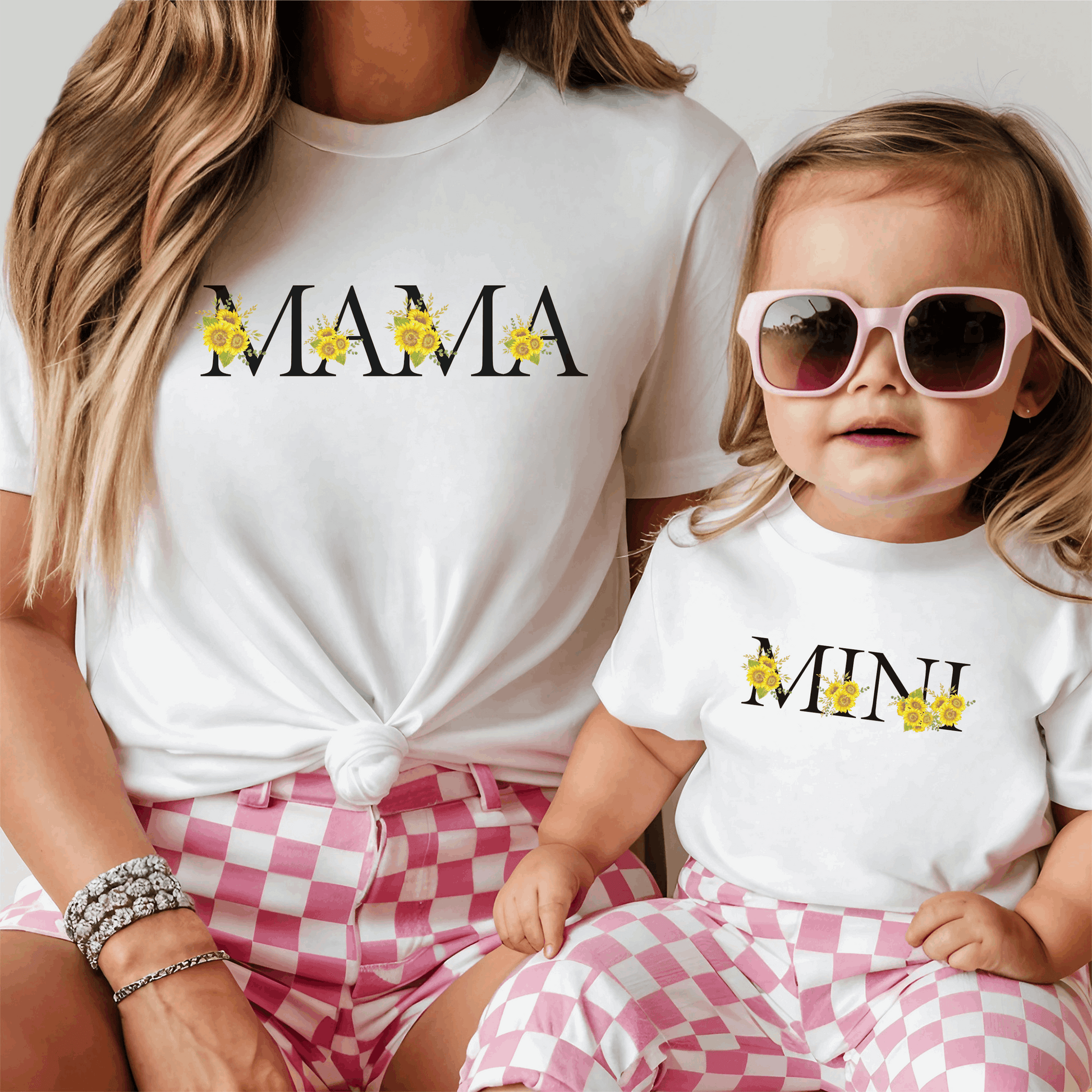 Mommy and Mini matching outfit featuring a MAMA sweatshirt and Mini Sunflower Baby Bodysuit in White or Pink Bella Canvas 100B fabric. The baby bodysuit displays charming sunflower “MINI” calligraphy, coordinating perfectly with the adult MAMA top for family photos, special occasions, or everyday wear. Soft, breathable, and comfortable, this matching family outfit is ideal for gifting, stylish parent-child moments, and creating memorable looks while keeping both mom and baby cozy and adorable.