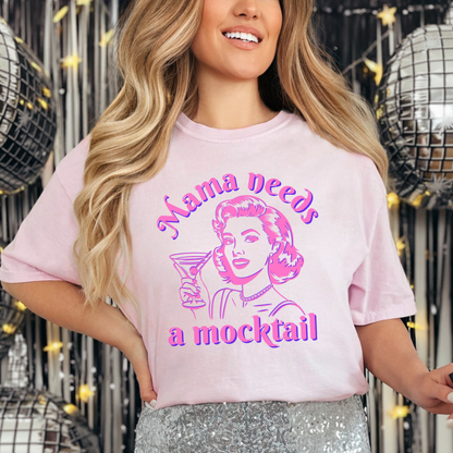 Image: A retro pop art inspired t-shirt featuring a hot pink neon design of a vintage mom holding a cocktail glass, with the phrase Mama Needs a Mocktail. Available in six colors, this Comfort Colors shirt is perfect for anyone celebrating sobriety, a newly pregnant mom, or a sober curious friend. A fun and stylish way to embrace a mocktail lifestyle while keeping it lighthearted and fashionable, by jaecrece.