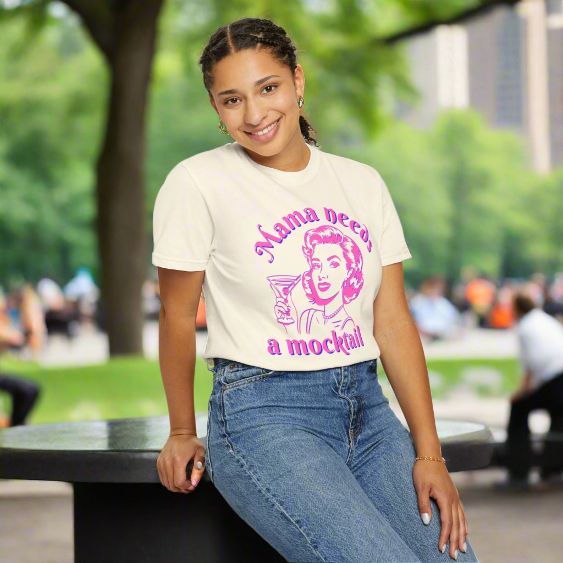 Image: A vintage inspired Mama Needs a Mocktail tee, featuring a playful pop art design of a retro mom toasting with a cocktail glass in bright pink neon. This Comfort Colors shirt is available in six chic shades, making it a perfect gift for sober curious friends, expecting moms, or those embracing a healthier lifestyle. A fun conversation starter that celebrates recovery and mindful drinking, by jaecrece.