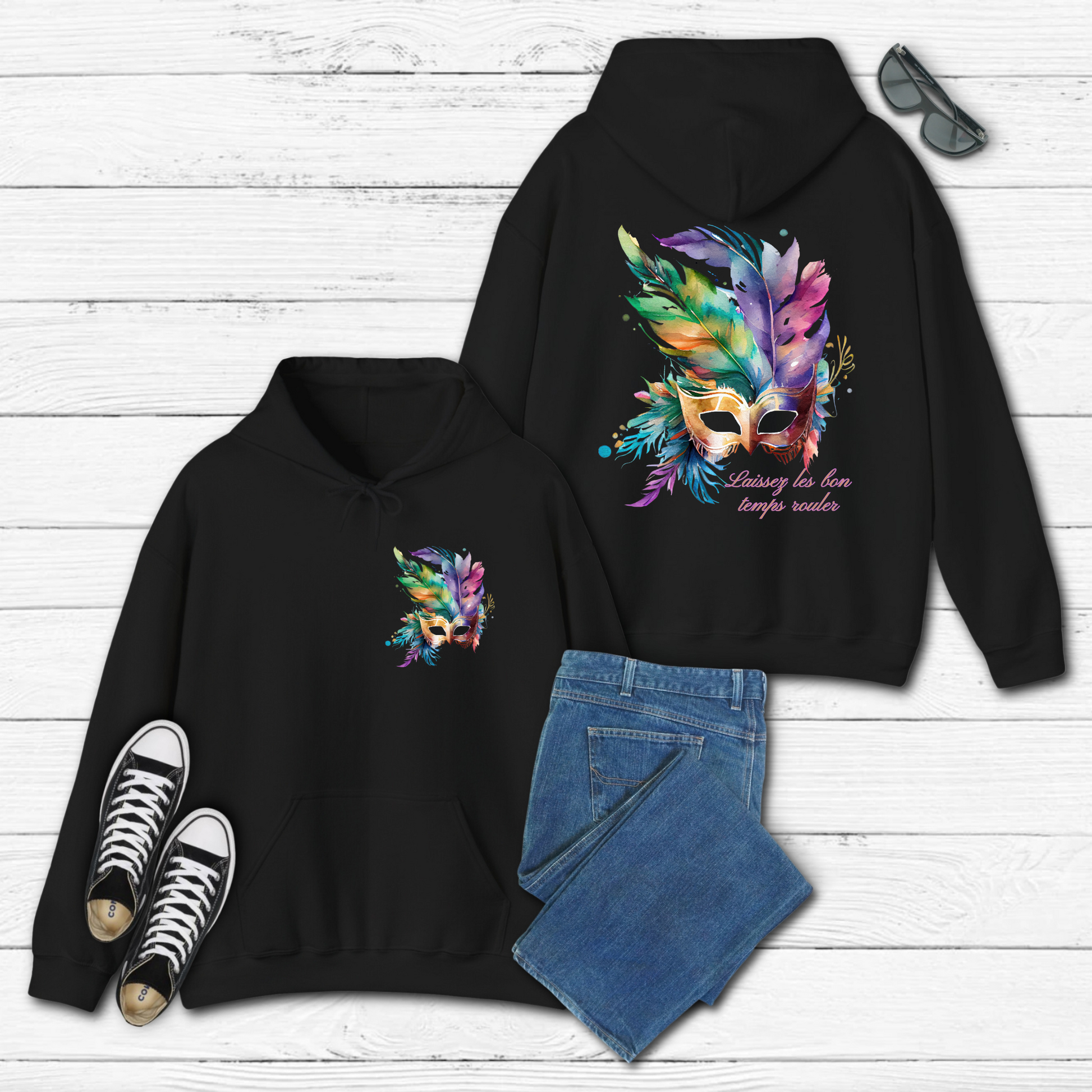Image: Black Adult Mardi Gras Hoodie, printed on front and back. The front of the sweatshirt has a watercolor carnival mask, and the back features an oversized graphic of the same party mask with the text Laissez les on temps rouler, by jaecrece