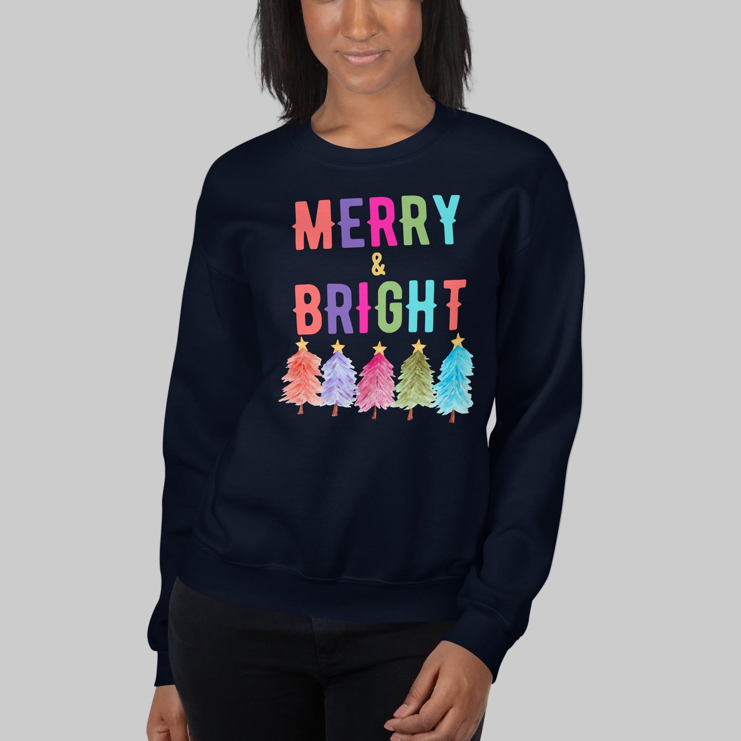 Stay cozy this holiday season with our Merry and Bright Christmas sweatshirt printed on a classic Gildan 18000 crewneck. Featuring colorful Christmas trees and festive lettering, this unisex sweatshirt is soft, warm, and available in white, navy, and black. With inclusive sizes from S to 5XL, this holiday sweatshirt is perfect for Christmas parties, family photos, or as a thoughtful gift for teachers, moms, and friends who love cheerful holiday outfits.