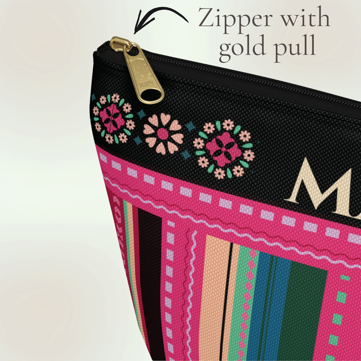 Close up of the gold zipper and black zipper tape on a personalized serape inspired cosmetic bag, showing the vibrant pink, teal, green, blue and black fabric details and colorful floral design on this personalized makeup and travel pouch