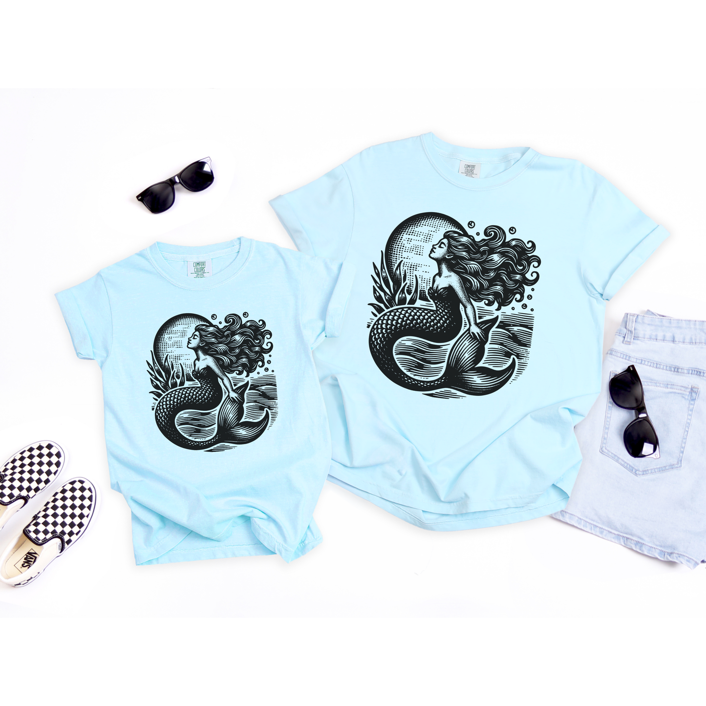 Coastal inspired girls graphic tee featuring a vintage style linocut inspired mermaid design with moonlit ocean waves and detailed seaside artwork. Soft garment dyed Comfort Colors youth shirt with a relaxed unisex fit perfect for beach trips casual summer outfits school days and matching family photos. Great for mermaid lovers ocean themed birthdays nautical aesthetic wardrobes and trendy coastal cowgirl fashion with a moody seaside vibe and timeless artistic feel.