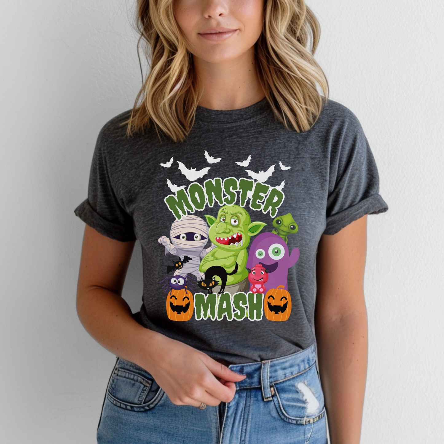 Monster Mash Halloween adult t shirt featuring cute cartoon monsters, mummy, trolls, pumpkins, black cat, bats and green slime lettering on a black or dark heather Gildan 2000 tee. Fun spooky season graphic shirt for women and men in sizes S through 5XL. Great for pumpkin patch visits, Halloween parties, school events, trick or treating nights, casual October outfits, funny Halloween tee, spooky cute fall shirt, monster graphic top for adults.