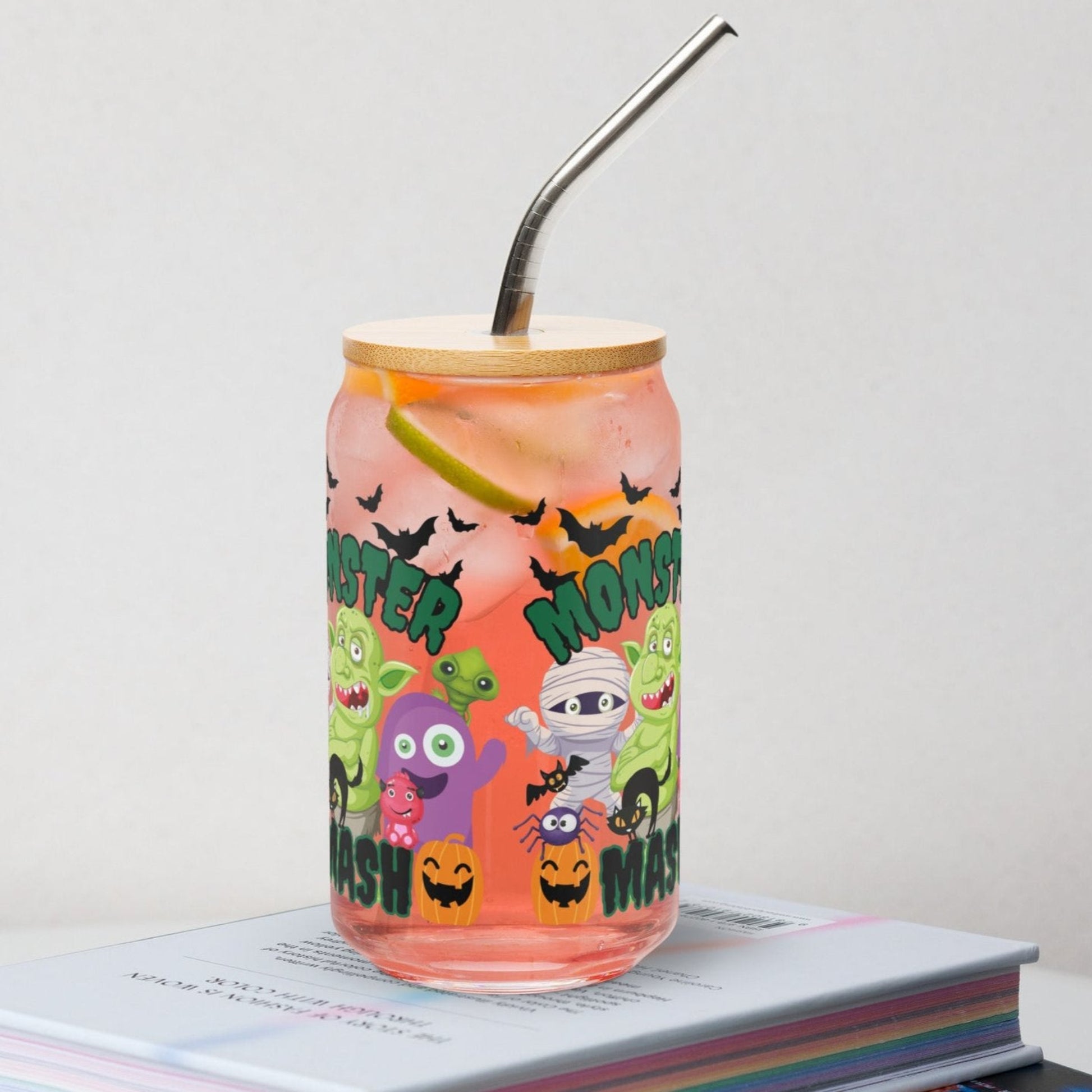Festive Monster Mash 16 oz sipper glass can with bamboo lid and straw, perfect for iced coffee, sodas, cocktails, or mocktails. Features playful monster illustrations, pumpkins, and bats for Halloween fun. Durable reusable drinkware that adds charm to fall gatherings, parties, or everyday sipping. Makes a thoughtful seasonal gift for friends, teachers, or family. Trendy Halloween glass cup, eco-friendly reusable beverage can for spooky season.