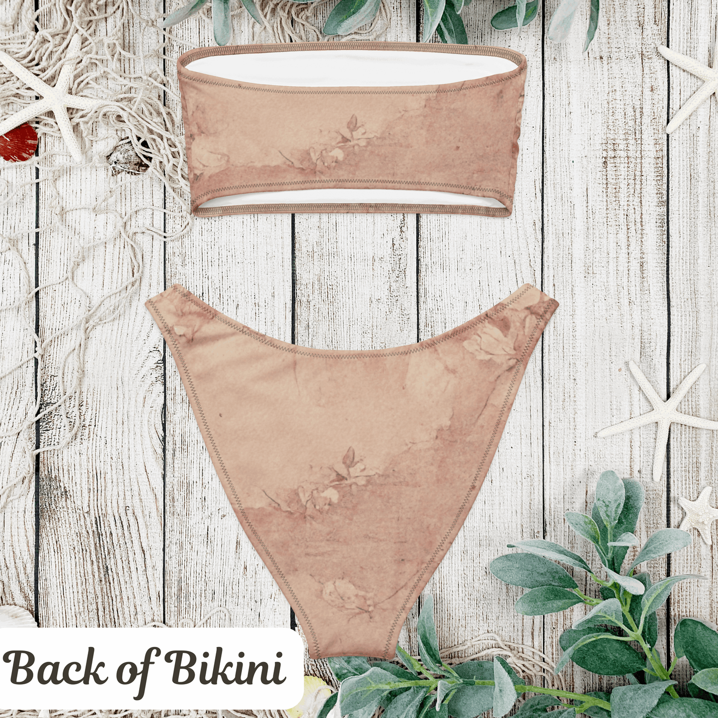 Back view flat lay of the Dusty Rose Cottagecore Bikini set on a weathered wood background with beachy vibes. The rear of the strapless bandeau top and V-cut high-leg bottoms shows smooth stitching and a flattering cut. Crafted from recycled polyester with UPF 50+ sun protection, this soft girl aesthetic swimwear offers comfort, style, and a romantic touch in sizes 2XS to 6XL.