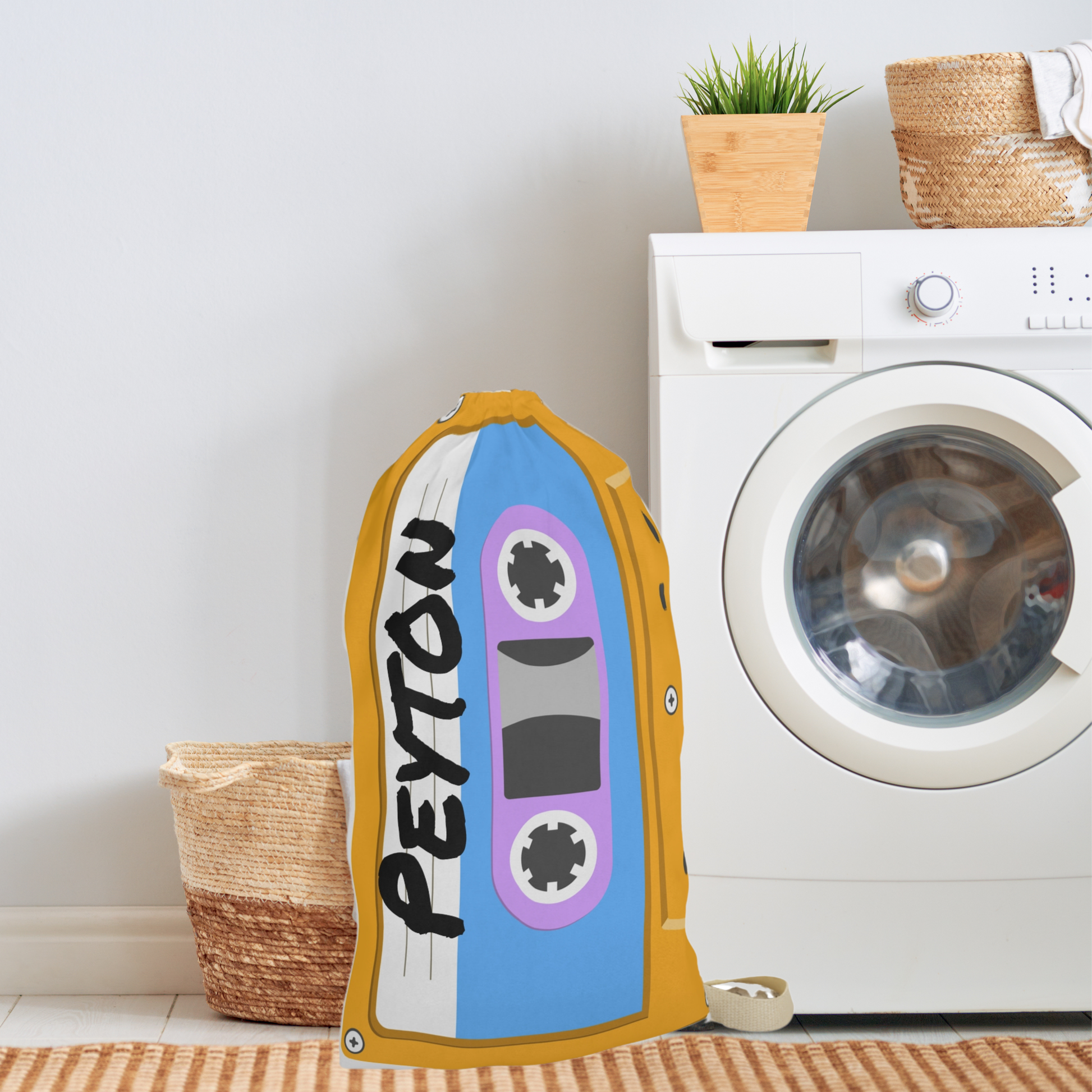 Large custom laundry bag featuring an all over cassette tape design in shades of orange, yellow, turquoise, and blue. Personalized text is incorporated into the design, creating a unique storage solution for everyday use. Drawstring closure helps keep contents secure while the shoulder strap allows comfortable transport. The 18 x 29 inch size is suitable for dorm rooms, kids bedrooms, camps, apartments, and laundry room organization.