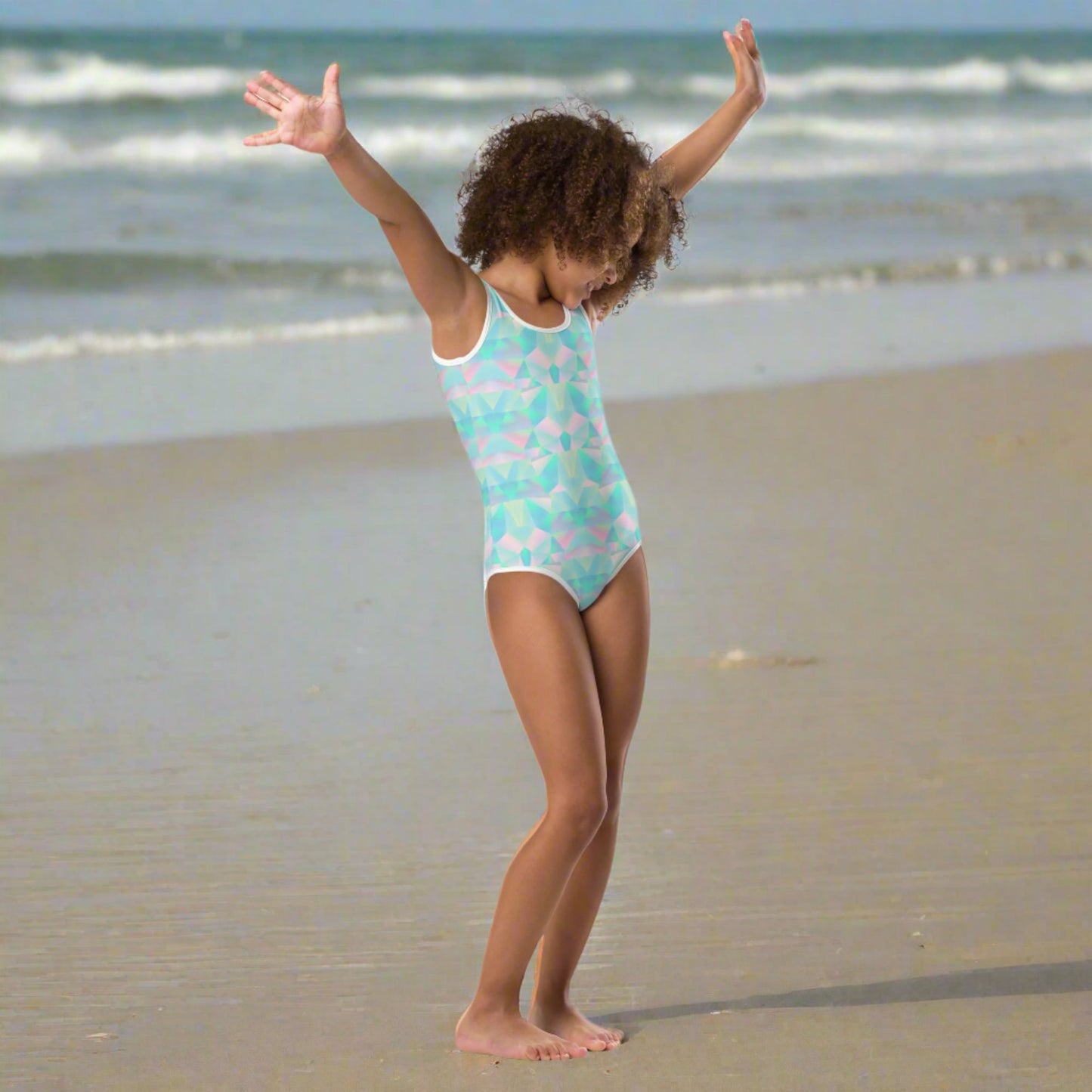 A colorful girls swimsuit featuring an abstract prism pattern in teal blue, soft pink, and purple brings a fresh pastel vibe to summer wardrobes. Sizes range from 2T through 20, making it easy for sisters of different ages to coordinate. Part of a matching family collection, this swimwear is great for vacations, beach outings, family portraits, tropical getaways, and thoughtful gifts for birthdays or the start of summer.