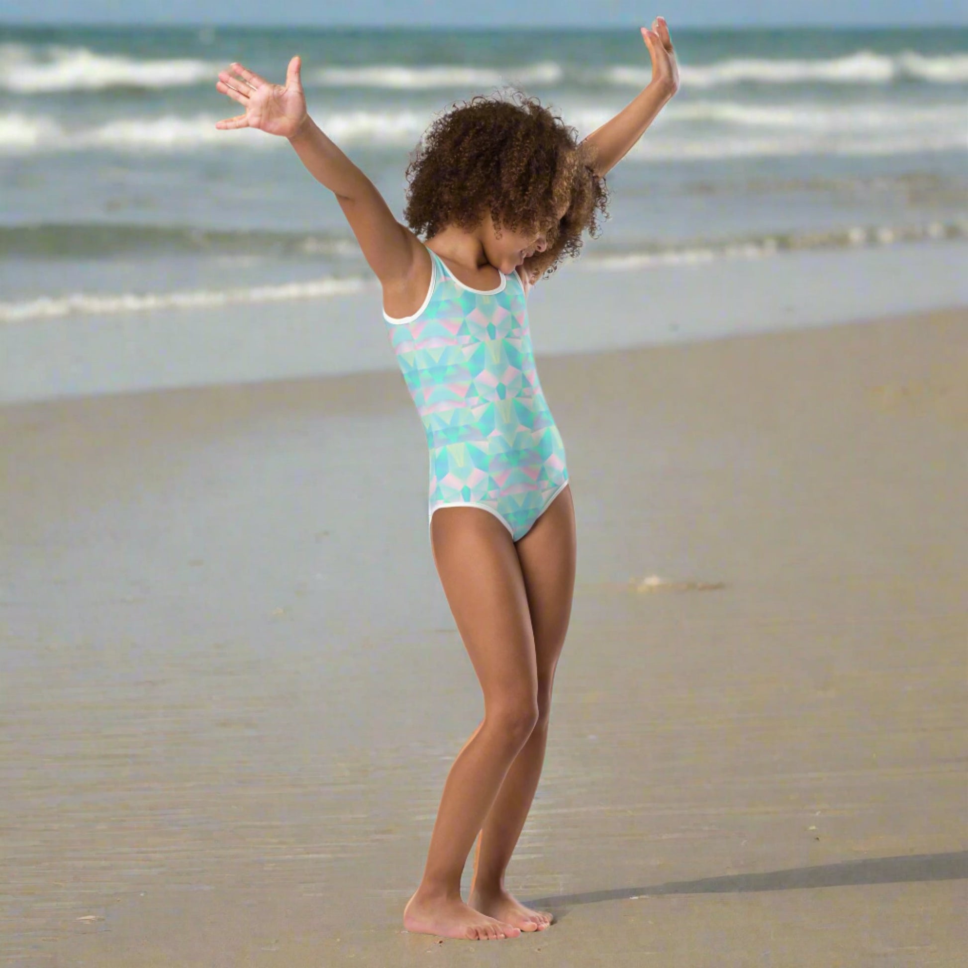 A colorful girls swimsuit featuring an abstract prism pattern in teal blue, soft pink, and purple brings a fresh pastel vibe to summer wardrobes. Sizes range from 2T through 20, making it easy for sisters of different ages to coordinate. Part of a matching family collection, this swimwear is great for vacations, beach outings, family portraits, tropical getaways, and thoughtful gifts for birthdays or the start of summer.