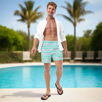 Man in light blue swim shorts with a pattern standing by a pool with palm trees in the background