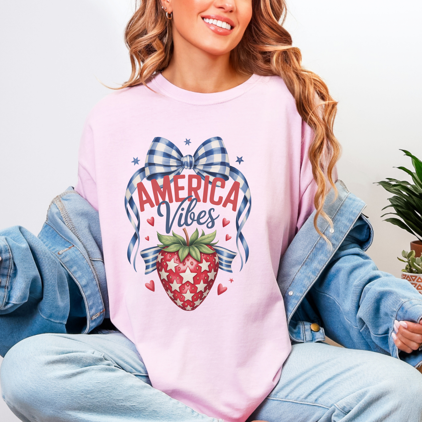 Patriotic strawberry Comfort Colors 1717 shirt in blossom featuring vintage Americana inspired artwork with a strawberry graphic gingham bow stars and heart accents. America 250 themed 4th of July t shirt with relaxed unisex fit and garment dyed cotton fabric. Perfect for mommy and me matching outfits patriotic family photos Memorial Day celebrations summer vacations and red white and blue holiday events for women who love nostalgic Americana style