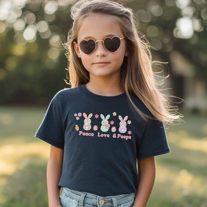 A child wearing sunglasses and a black short sleeve tee with a graphic that includes cute bunny designs and the text 'Peace Love & Peeps'.