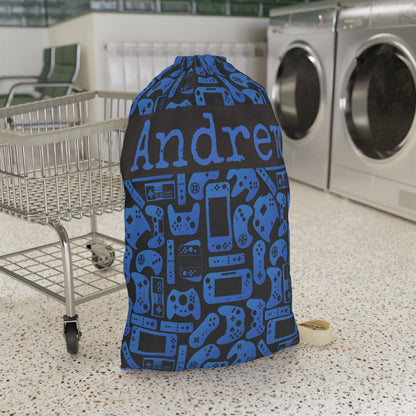 Personalized blue and black gamer laundry bag featuring a playful pattern of video game controllers and handheld consoles. Custom name text makes this reusable laundry bag a fun choice for boys, girls, kids, teens, sleepaway camp, college dorms, travel, or keeping dirty clothes organized at home.