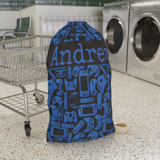 Personalized blue and black gamer laundry bag featuring a playful pattern of video game controllers and handheld consoles. Custom name text makes this reusable laundry bag a fun choice for boys, girls, kids, teens, sleepaway camp, college dorms, travel, or keeping dirty clothes organized at home.