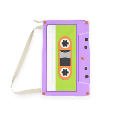 Large custom laundry bag featuring an all over cassette tape design in shades of purple, pink, turquoise, and blue. Personalized text is incorporated into the design, creating a unique storage solution for everyday use. Drawstring closure helps keep contents secure while the shoulder strap allows comfortable transport. Suitable for dorm rooms, kids bedrooms, camps, apartments, and laundry room organization.