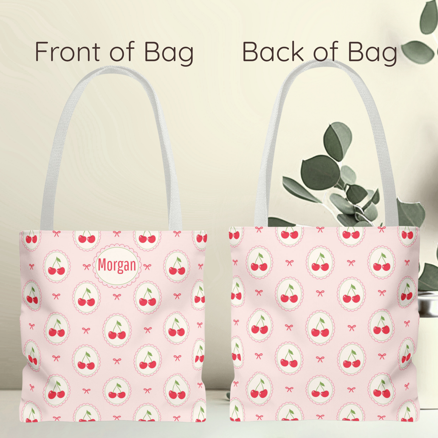 A pink tote bag shown from both front and back, with a repeating cherry print and a circular patch reading “Morgan” on the front. The image includes text labels “Front of Bag” and “Back of Bag,” with a soft beige background and decorative leaves on the right. Personalized pink tote bag decorated with repeating cherry medallions and delicate bows on a soft blush background. This Kawaii inspired cherry aesthetic accessory has a playful Cutecore and Coquette feel and makes a cute teacher gift, tween girl gift.