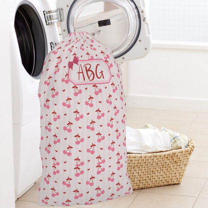 Personalized laundry bag with a sweet coquette cherry design and custom name personalization, offering a stylish solution for organizing clothes at home or on the go. The roomy drawstring construction easily accommodates a full load of laundry, making it perfect for college move in, summer camp, boarding school, sleepovers, and vacations. This charming laundry sack blends everyday function with a soft feminine aesthetic and makes a beautiful personalized gift for all ages.