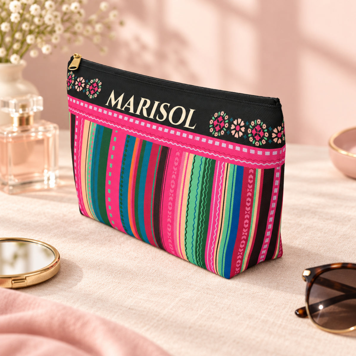 Personalized colorful serape inspired makeup bag with custom name, floral details, vibrant pink, teal, green and blue stripes, black accents, gold zipper, and spacious travel pouch for Latina gifts, quinceañera gifts, makeup, toiletries, and travel