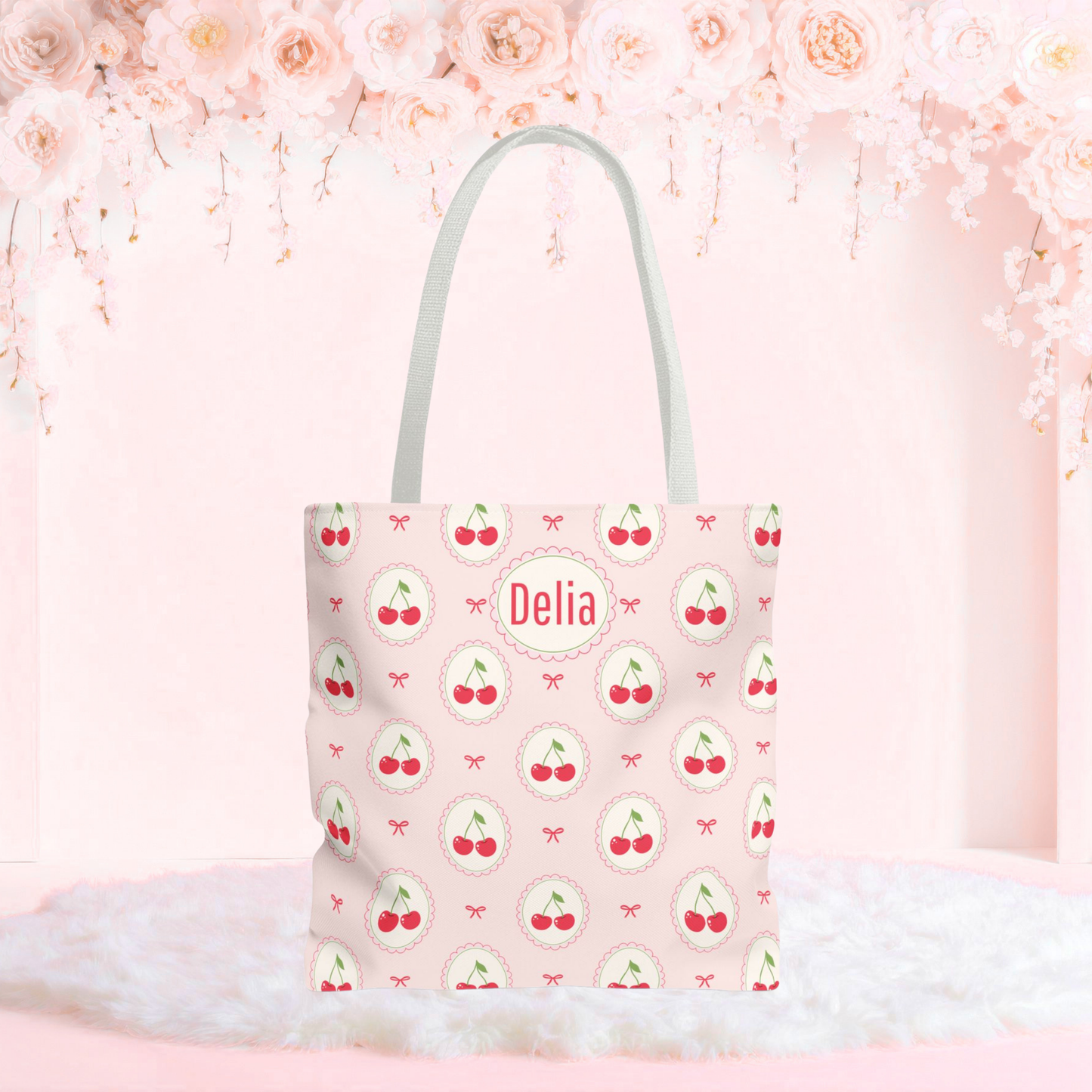 Personalized cherry tote bag with a soft pink background, repeating cherry medallions, and delicate bow accents. This custom cherry tote has a playful Cutecore and Coquette aesthetic and can be personalized with a name or monogram, making it a cute accessory for school, shopping, travel, or everyday use.