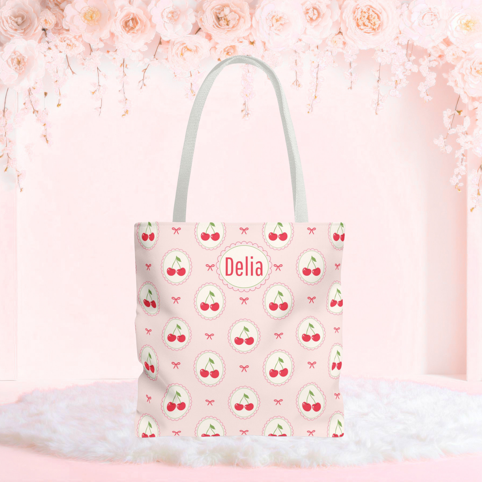 Personalized cherry tote bag with a soft pink background, repeating cherry medallions, and delicate bow accents. This custom cherry tote has a playful Cutecore and Coquette aesthetic and can be personalized with a name or monogram, making it a cute accessory for school, shopping, travel, or everyday use.