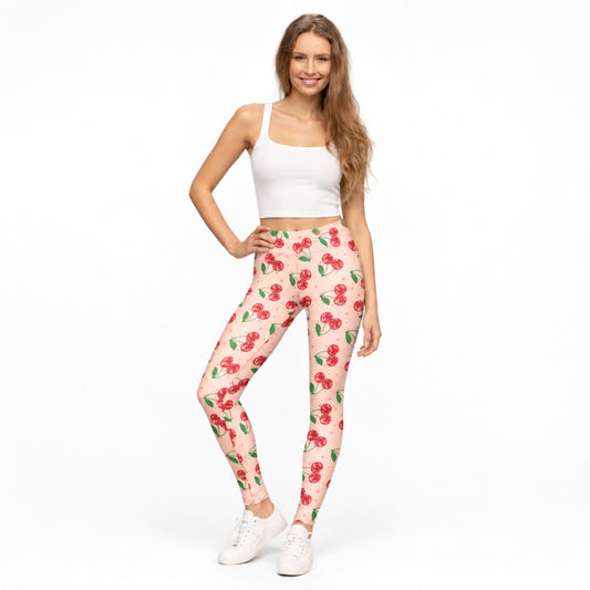 Pink cherry print womens leggings featuring a bright pink background with sparkling red cherries and playful decorative details. These full length leggings have a comfortable mid rise fit and colorful retro style that works beautifully for Cherry Girl fashion, cute casual outfits, nostalgic looks and fun everyday wear.