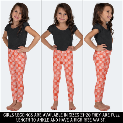 Full length view of girls Christmas leggings with a high rise waistband and ankle length fit. The leggings feature a soft pink background covered with cream Christmas trees and red geometric details for a colorful holiday look. Available in sizes 2T through 20, the wide size range makes this style suitable for toddlers, kids, tweens, and teens looking for comfortable Christmas clothing.