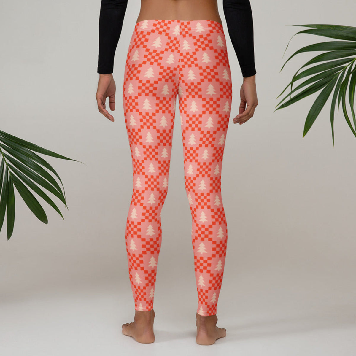 Pink Christmas tree leggings with a playful pattern of cream evergreen trees and red geometric details on a soft pink background. The nostalgic holiday design makes these women's leggings a fun gift idea for someone who loves Christmas clothing, cozy winter fashion, or unique holiday prints. The full length style and comfortable mid rise waistband make them practical as well as festive.