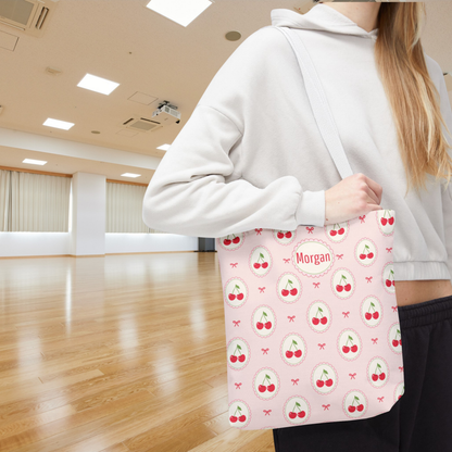 Pink cherry tote with a playful Coquette and Cutecore inspired design featuring repeating cherry medallions, delicate bows, and a soft pastel background. Personalized with a name or monogram, this cute accessory makes a thoughtful tween girl gift, teen girl gift, or teacher gift.
