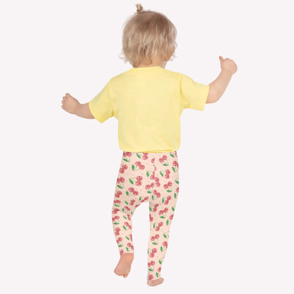 Cherry print girls leggings featuring a soft pink background with scattered red cherries and green stems, designed with a high rise waistband and full length fit. These kids leggings offer soft stretch fabric for comfort and flexibility, making them ideal for school outfits, dance practice, gymnastics, or everyday play. A playful fruit pattern design that combines cute style with durable activewear for girls who love fun, colorful fashion.