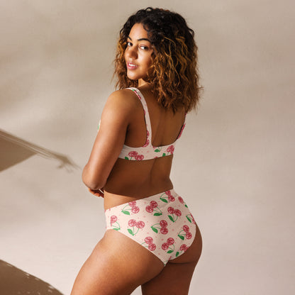 A blush pink high waisted bikini covered in sparkling disco cherries creates a playful and feminine look for sunny adventures. This recycled two piece swimsuit features double layered fabric, removable pads, and a flattering silhouette designed for all day comfort. Available in sizes Small through 3XL, it coordinates with matching swimwear for women, men, and children, making it a fun choice for family vacations and coordinated beach outfits.