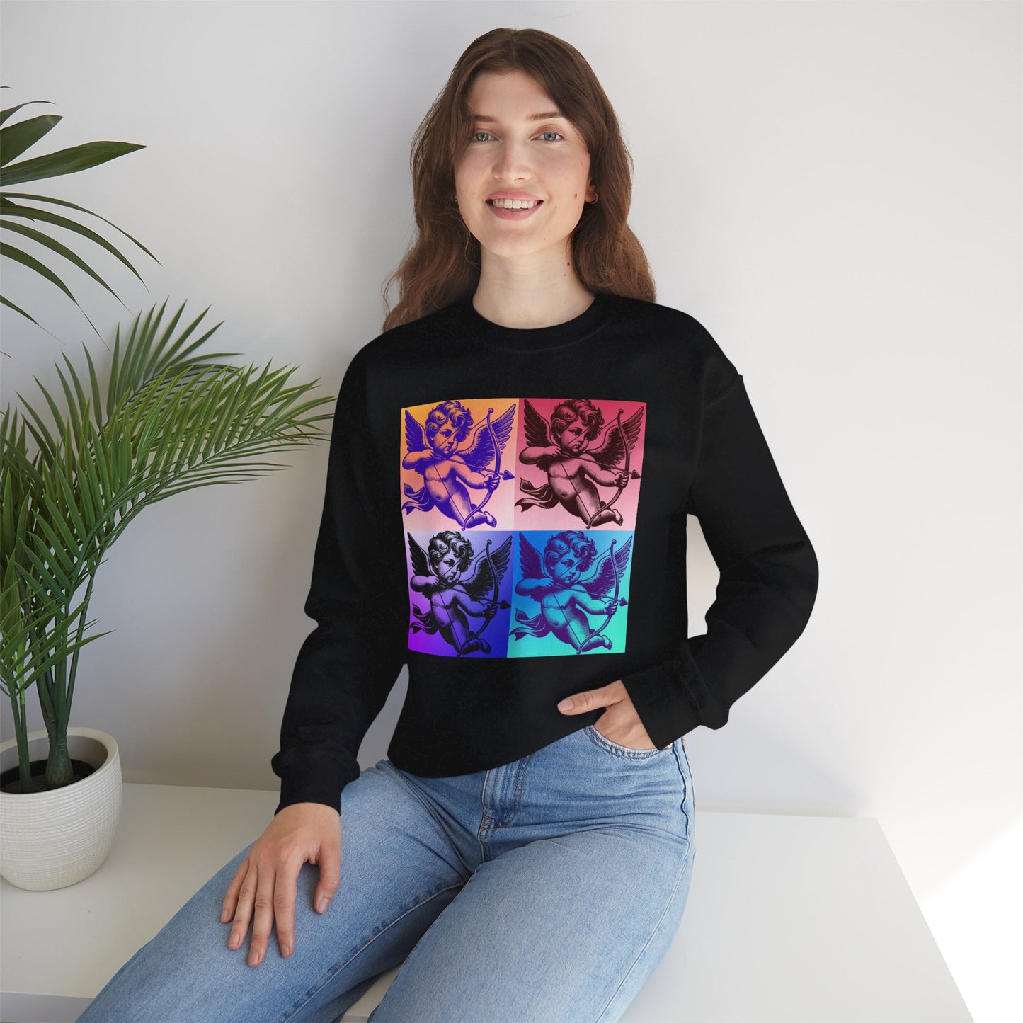 Model wearing a pop art cupid crewneck sweatshirt printed on a cozy Gildan 18000 fleece. The bold angel graphic features a four panel pop art style that stands out against the black fabric. This sweatshirt is available in black and white, sizes Small through 5XL, and offers a body inclusive plus size friendly fit. Matching adult and child options make it great for Mommy and Me outfits and family matching looks.