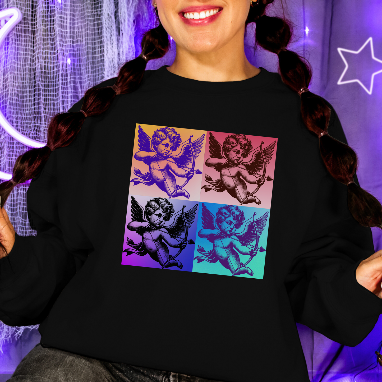 Close up of a pop art cupid sweatshirt worn by a woman, showcasing a colorful four square cupid design inspired by vintage angel artwork. Printed on a soft Gildan 18000 crewneck sweatshirt in black or white, this cozy pullover offers inclusive sizing from Small to 5XL. Also available as a t shirt and in child sizes, making it ideal for Mommy and Me outfits, Valentine season looks, and artsy everyday wear.