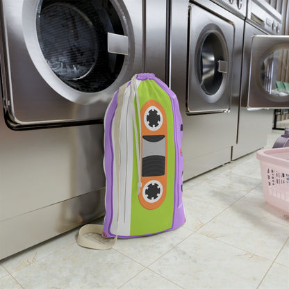 Personalized laundry bag with a retro cassette tape pattern displayed across a purple background. The custom name is printed directly onto the fabric, creating a unique and practical storage accessory. A drawstring top gathers closed to help keep clothing contained, while the woven shoulder strap makes carrying easy. Designed for everyday use, the spacious interior accommodates clothing, towels, bedding, and other essentials for home, college, camp, or travel.