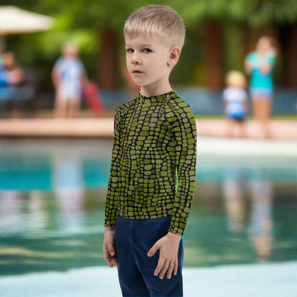 All-over reptile print kids rash guard in sizes 2T–7, featuring green scales inspired by snakes, dinosaurs, and lizards. This long-sleeve swim top offers sun protection and costume-ready design, great for imaginative toddlers. Perfect for themed pool parties, beach games, and outdoor summer fun. Soft, stretchy fabric keeps little ones comfy and stylish.