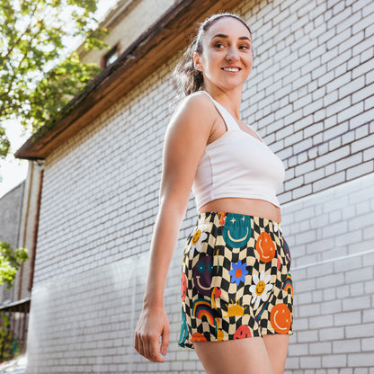 Smiley face checkerboard athletic shorts featuring a retro beige and black wavy checker pattern with playful smiley face accents, designed as unisex workout shorts with a comfortable elastic waistband and flat white drawstring. These breathable athletic shorts are made from moisture wicking recycled polyester fabric with four way stretch, mesh side pockets, and a 2.5 inch inseam, making them perfect for gym workouts, sports, running, lounging, and casual athleisure wear, available in inclusive sizes XS to 3
