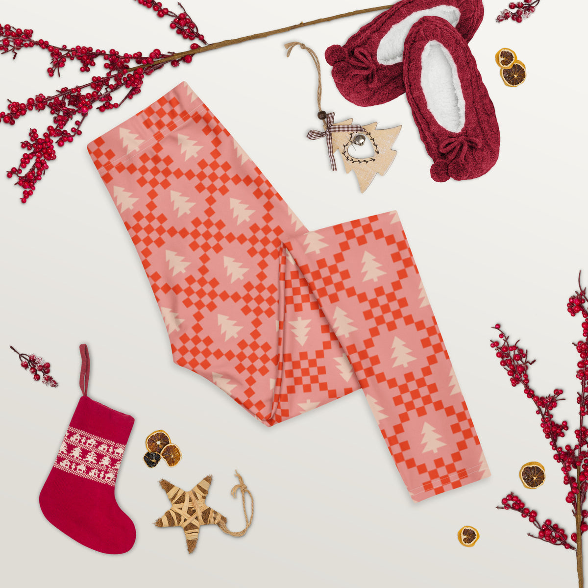A playful pair of women's leggings featuring a retro inspired Christmas pattern with cream evergreen trees and red geometric shapes arranged across a pink background. The nostalgic print has the feel of a vintage holiday sweater while offering the comfort and flexibility of leggings. The design is ideal for women who enjoy festive clothing with a softer, more colorful look than traditional Christmas patterns.