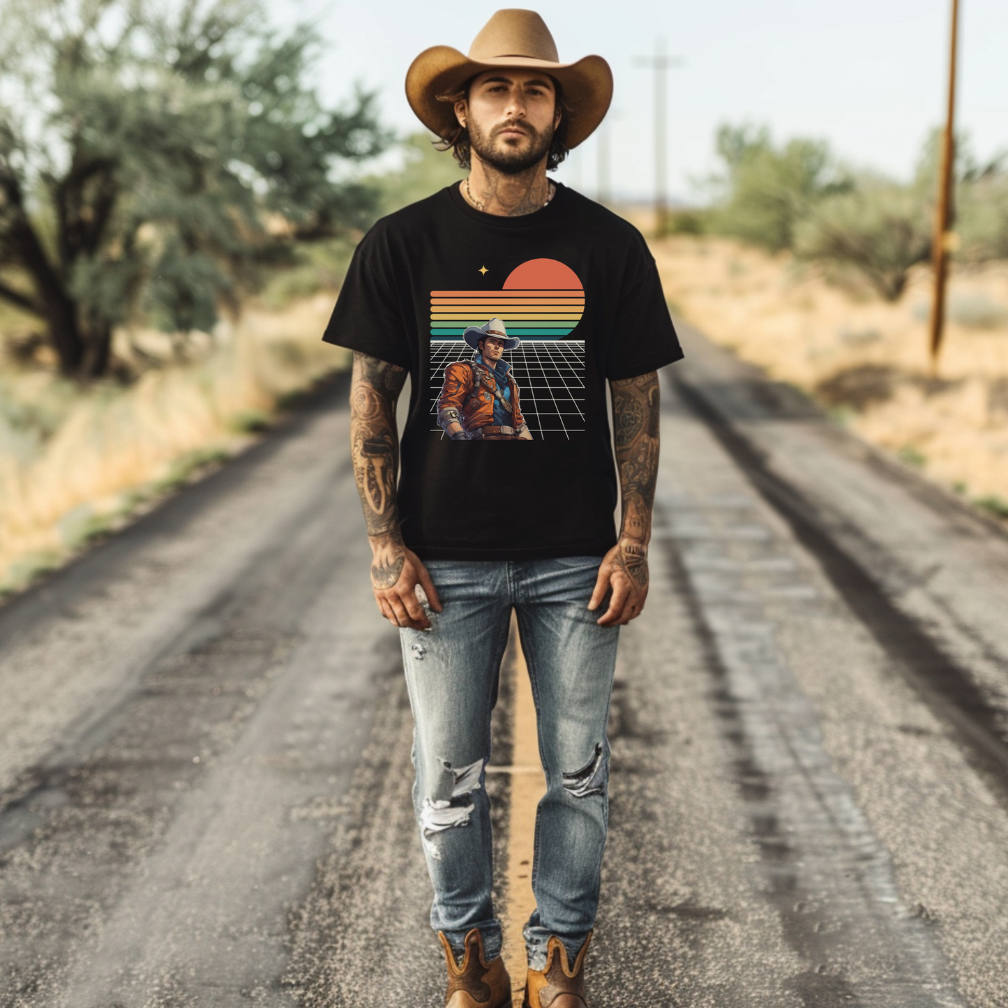 Man wearing a black t-shirt with an epic space cowboy retro futuristic graphic design, standing on a dirt road.