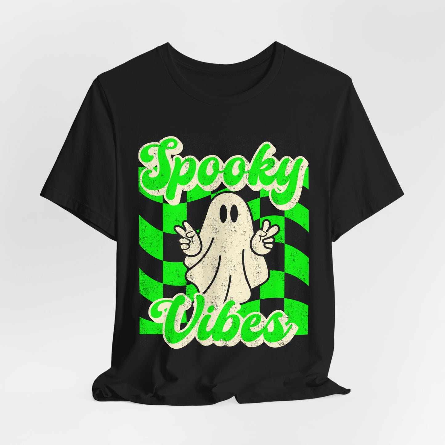 Retro Halloween ghost tshirt on a black Bella Canvas 3001 featuring a peace sign ghost and bold green checkerboard design with Spooky Vibes text. Lightweight soft cotton unisex shirt in sizes S to 3XL plus matching kids sizes for sibling and family matching sets. Ideal for boo crew events, school spirit days, Halloween travel outfits, haunted attractions, costume alternative looks, and stylish spooky season wardrobes all October long.