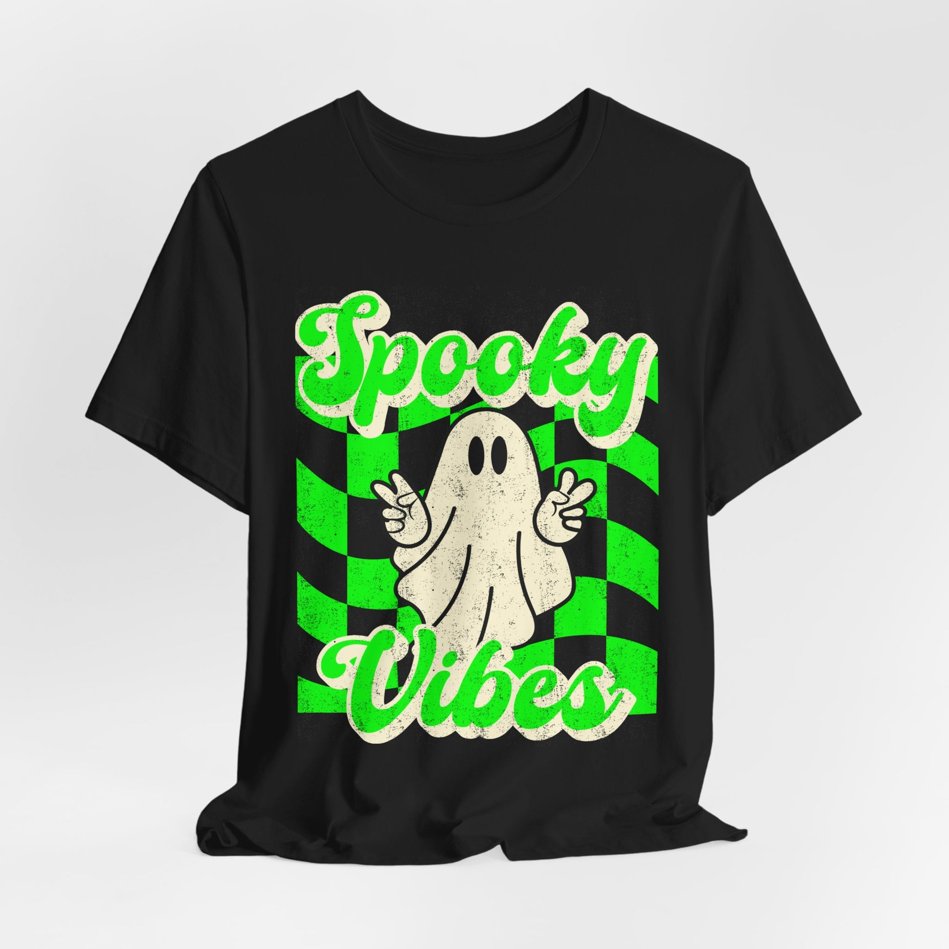 Retro Halloween ghost tshirt on a black Bella Canvas 3001 featuring a peace sign ghost and bold green checkerboard design with Spooky Vibes text. Lightweight soft cotton unisex shirt in sizes S to 3XL plus matching kids sizes for sibling and family matching sets. Ideal for boo crew events, school spirit days, Halloween travel outfits, haunted attractions, costume alternative looks, and stylish spooky season wardrobes all October long.