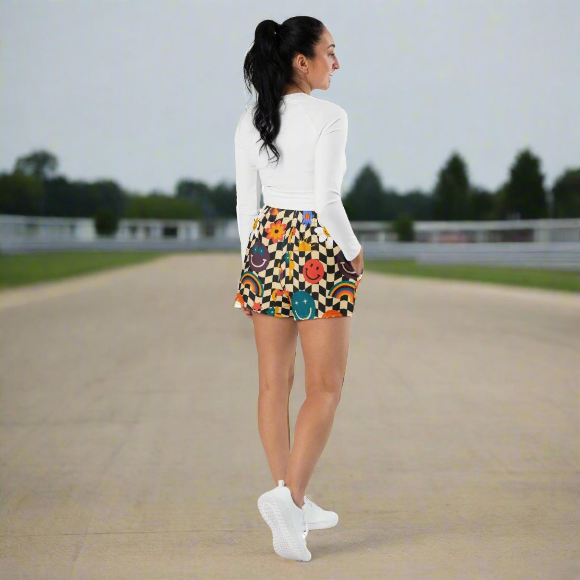 Retro smiley face checkerboard unisex athletic shorts shown from the front, highlighting the bold beige and black wavy checker pattern and smooth lightweight fabric. These fast drying workout shorts feature breathable moisture wicking microfiber material, a comfortable elastic waistband with drawstring, and a short 2.5 inch inseam for easy movement, making them ideal for activewear, summer workouts, festivals, travel, and casual everyday wear while coordinating with matching leggings for family matching out