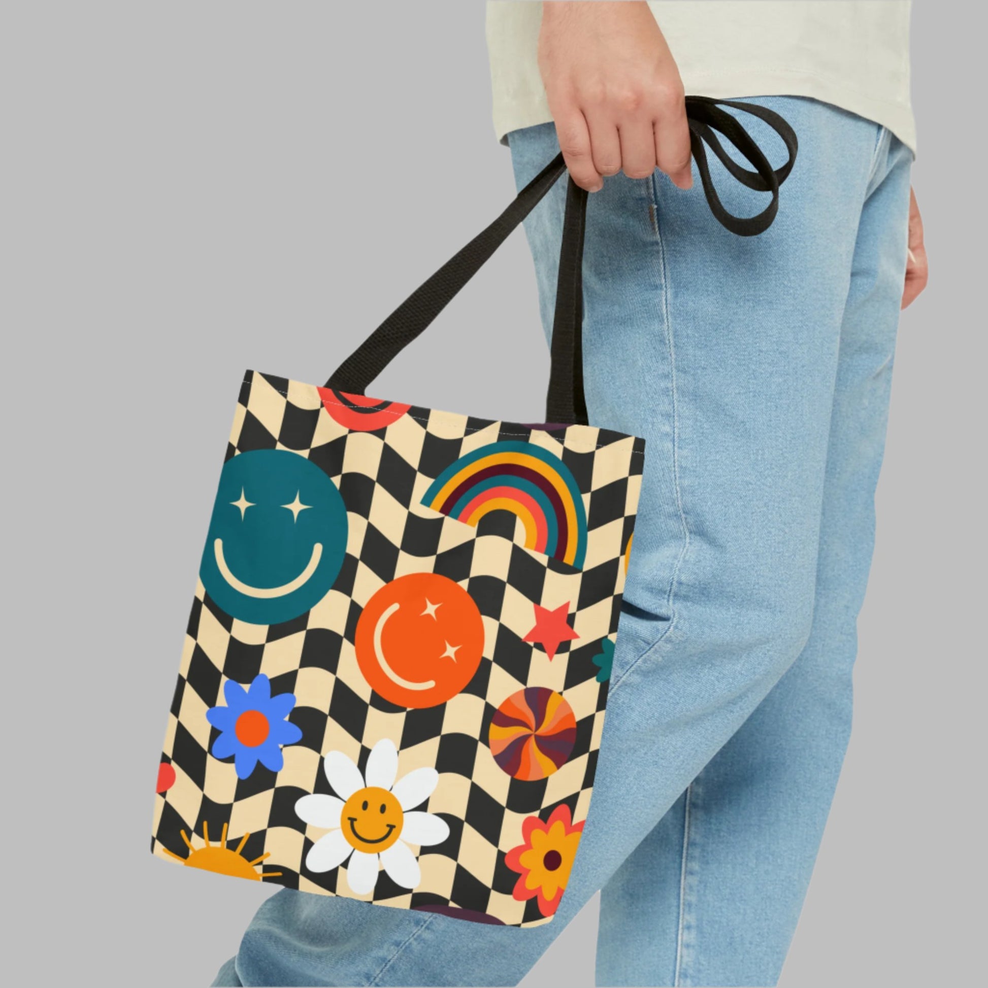 Smiley Face Checkerboard Canvas Tote Bag. This cute reusable carryall is eco friendly, and features a black and khaki checkerboard background, with smiley face, rainbow and daisy graphics. by jaecrece.com