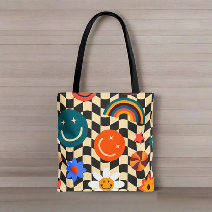 Smiley Face Checkered Canvas Tote Bag. This cute reusable carryall is eco friendly, and features a black and khaki checkerboard background, with smiley face, rainbow and daisy graphics. by jaecrece.com