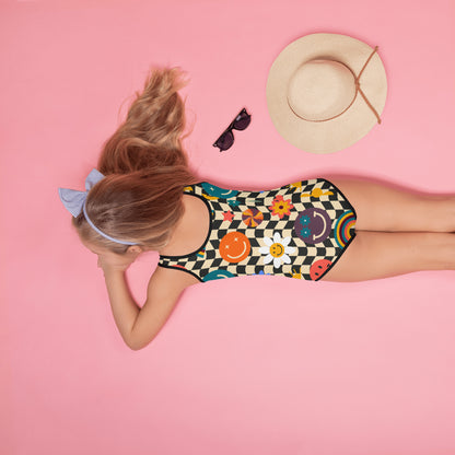 Smiley Face Checkerboard Girls One Piece Swimsuit featuring retro rainbow, daisy, and smiley face print on beige and black wavy checkerboard fabric.