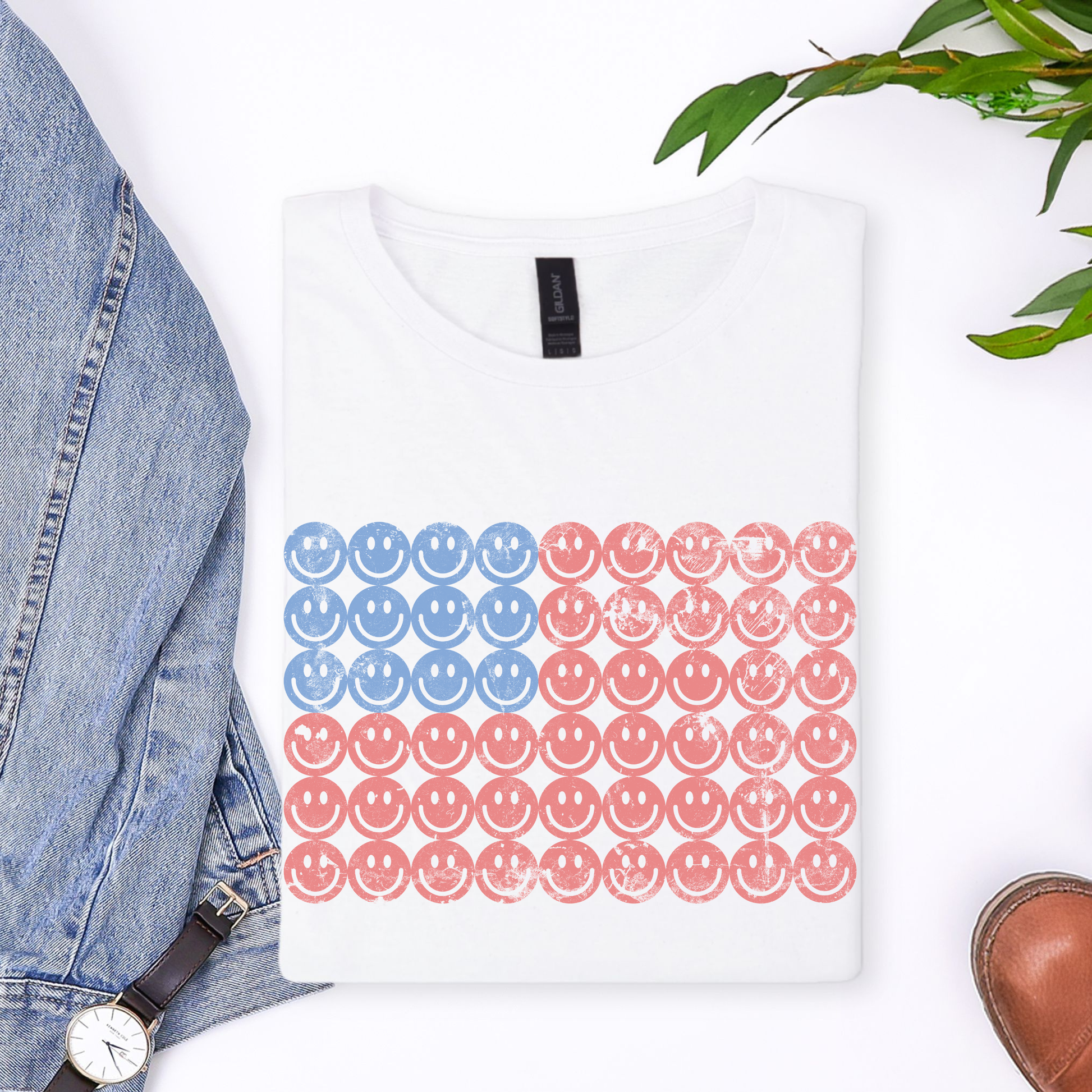 Flatlay photo of a smiley face American flag graphic tee on a white cotton shirt, colorful USA patriotic shirt design, cute Fourth of July outfit idea and red white blue summer apparel