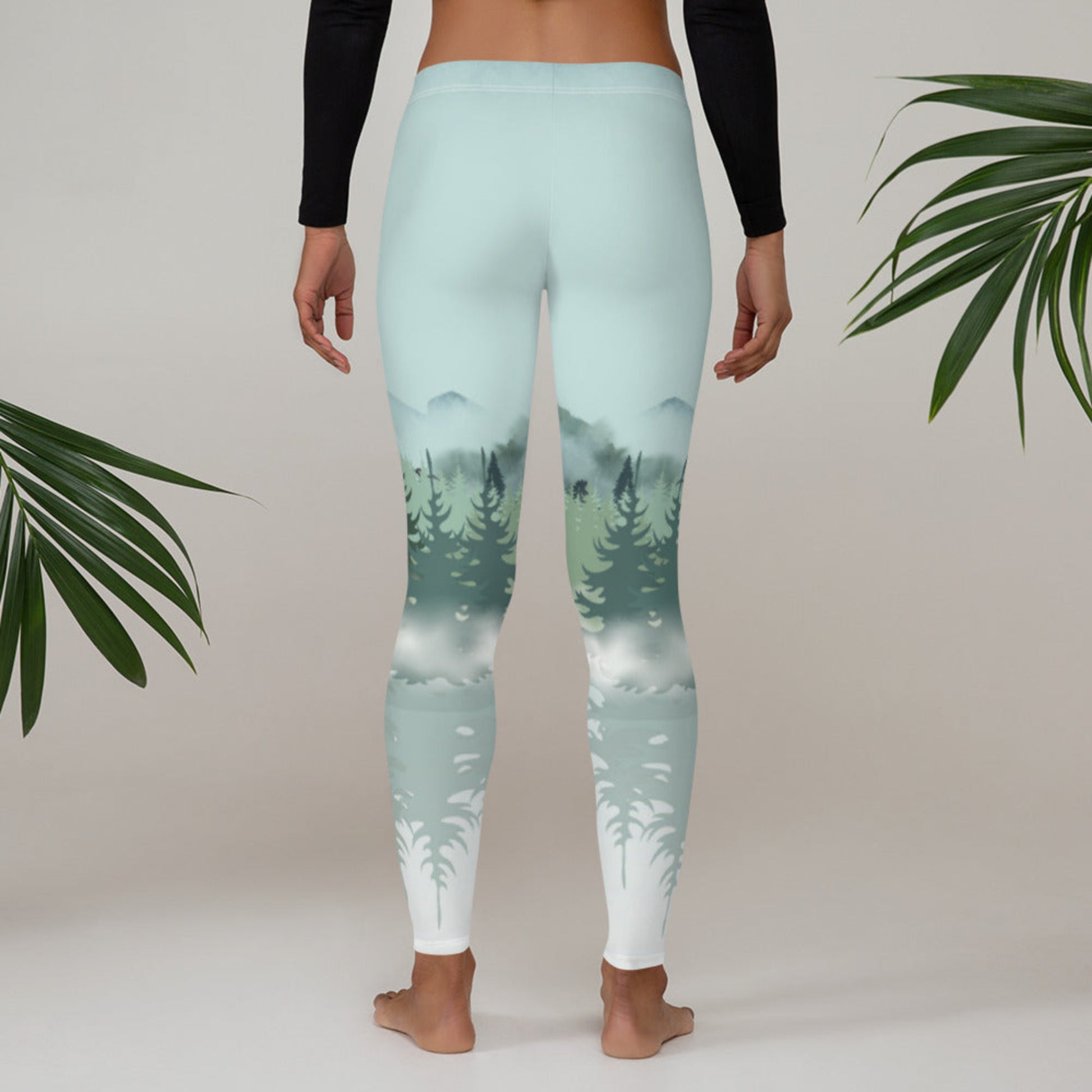 Women’s winter forest leggings with a mid rise waist and full length design, featuring a snowy pine forest scene in shades of green, blue, and gray. These leggings are perfect for casual wear, cozy winter outfits, or outdoor adventures. Great for nature lovers, gift giving, or fans of women’s active clothing, offering comfort, style, and a serene forest inspired look for all day wear.