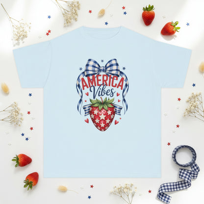 Soft Comfort Colors 9018 girls patriotic strawberry shirt inspired by vintage Americana and America 250 celebrations. Features strawberry artwork with gingham bow stars and heart accents on garment dyed cotton fabric. Relaxed fit youth tee perfect for 4th of July outfits mommy and me matching looks Memorial Day family gatherings patriotic vacations and summer holiday wear
